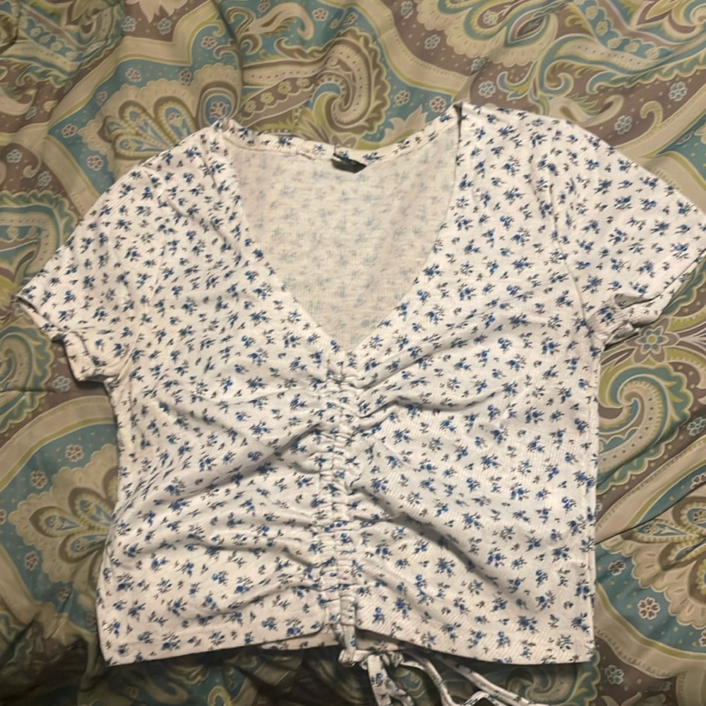 white crop top with blue flowers and a drawstring in the front